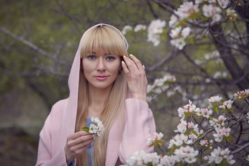 Spring bloom concept. Girl on dreamy face, tender blonde near violet flowers of judas tree, nature background.