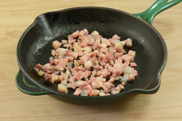 Chopped pancetta bacon in cast iron frying pan with olive oil