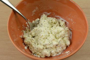 Close up of mixing herbs into ricotta cheese in orange bowl with spoon