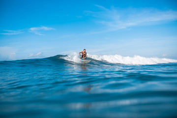 young active man riding on waves on sunny day in ocean