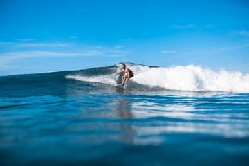 handsome sporty man riding on waves on sunny day in ocean