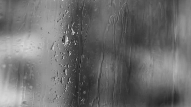 Footage of water and rain on a glass window on a grey rainy day