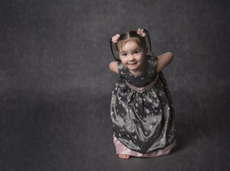 Toddler girl in pretty dress and bare feet with hands behind her back