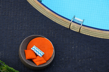 Pool chair on black tiles floor besdie swimming pool