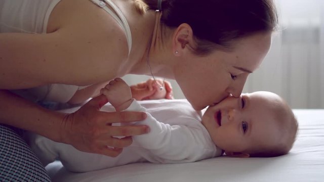 Mom with her child smiling and laughing at home on bed