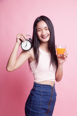 Asian woman with a clock drink orange juice.