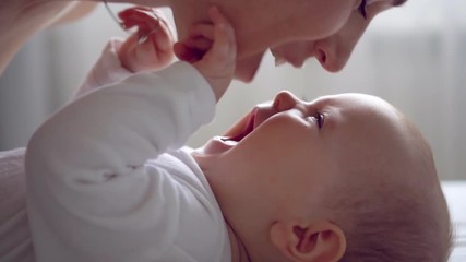 Mother kissing her adorable baby girl on bed - Powered by Adobe