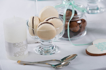 macarons in a glass crockery, next to other sweets and desserts, festive table