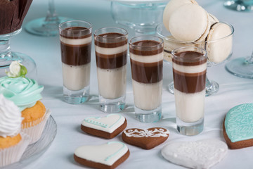 chocolate desserts in glasses surrounded by gingerbread, sweets and other sweets on the festive table, candy bar for the wedding