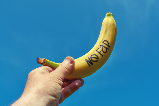 Banana with inscription "nofap" in man hand. Concept sexual problems.