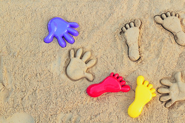 Sand on the beach or in the sandbox and footprints in the sand. A form for sand nearby. Can be used as a background image to copy space.