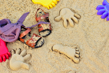 Sand on the beach or in the sandbox and footprints in the sand. Form for sand and children's shoes nearby. Can be used as a background image to copy space.