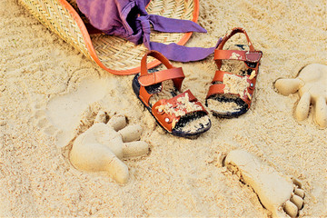 Sand on the beach or in the sandbox and footprints in the sand. Form for sand and children's shoes nearby. Nearby accessories to protect the sun rays of parents. Background image for copy space.