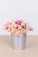 Bouquet of pink roses in vintage pot on wooden background.
