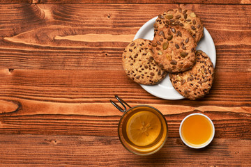 Biscuits with seeds placed near cup of tea and honey