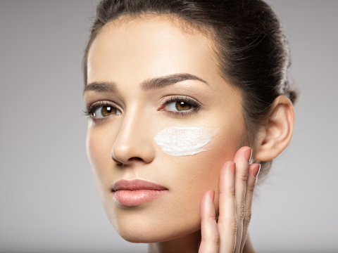 Beautiful face of young woman with cosmetic cream  on face