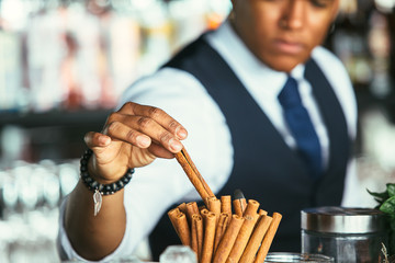 Detail of the hand of a bartender takes cinnamon stick