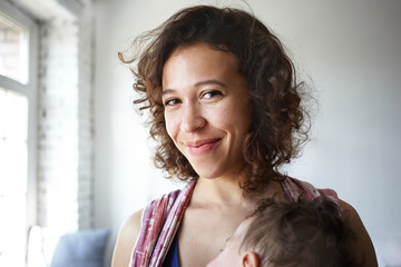 Close up shot of beautiful positive young Latin female smiling joyfully at camera, satisfied with...