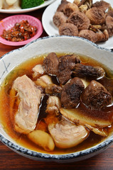 Bowl of chicken soup with agaricus mushrooms on wooden table . 