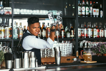Expert barman adds alcohol to a shaker