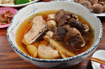 Bowl of chicken soup with agaricus mushrooms on wooden table . 