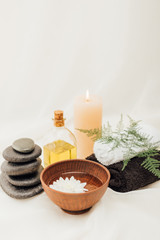 Obraz na płótnie Canvas arrangement of spa treatment accessories and chrysanthemum flower in wooden bowl on white background