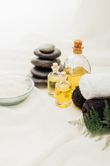 close up view of arrangement of spa treatment accessories with essential oil, pebbles and salt on white background