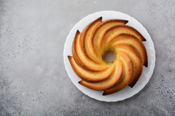 Bundt cake with sugar glaze and coconut on dark grey old concrete background. Selective focus. Top view with copy space.