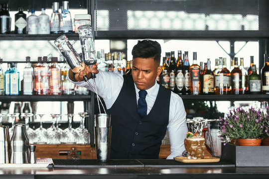 Expert bartender adding alcohol to a shaker