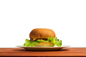 Homemade hamburger on a white plate, on a wooden table. Fast and harmful food. Isolate on white background.