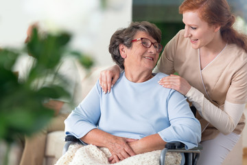 Friendly relationship between smiling nurse and happy disabled grandmother