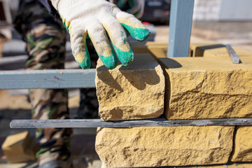 man builds a brick wall at a construction site