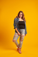 Joyful curvy girl in casual outfit posing at studio