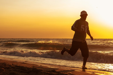 A man runs along the seashore at dawn or sunset