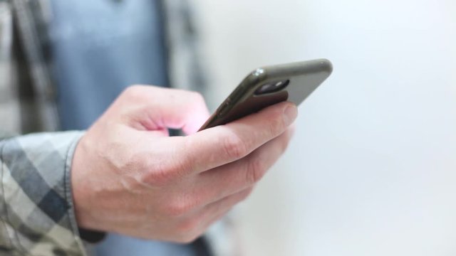 Stylish young man in a plaid shirt uses a smartphone