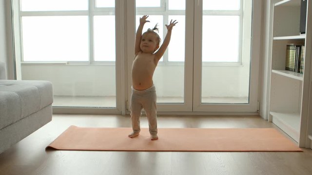 Funny babe pulls his hands up on the rug for yoga
