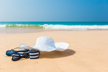 hat, sun glasses and flip flops over the sand