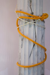 Broken gypsum column tied with cord as a concept of modern art