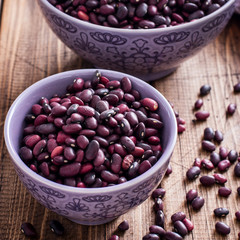 Red dry beans in a ceramic bowl on a wooden table, square