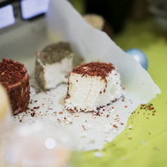 Pieces heads of soft cheeses with different spices and additives on wooden market board. Gastronomic dairy produce, real scene in the food market