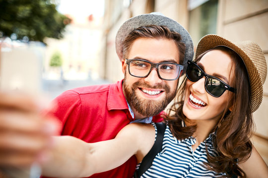 Portrait of cheerful young couple taking selfie together in the summer outdoors