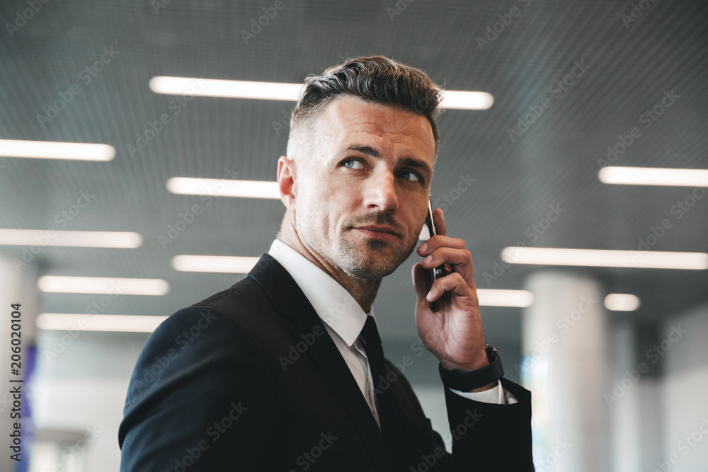 Poster handsome mature businessman talking on mobile phone