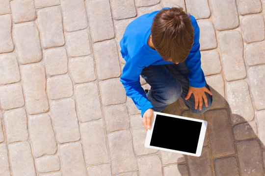 Child with tablet computer outdoors. Top view.