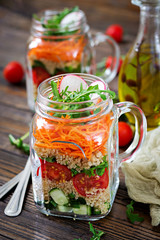 Salads with quinoa,  arugula, radish, tomatoes and cucumber in glass  jars on  wooden background.  Healthy food, diet, detox and vegetarian concept