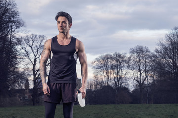 Fototapeta premium Male runner taking a water break after a cool winter evening run