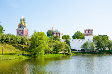 Novodevichy Convent, also Bogoroditse-Smolensky Monastery located in the southwestern part of Moscow on bank of the Moscow River during early summer seen from the pond in Moscow , Russia. - obrazy, fototapety, plakaty