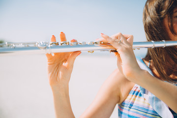Young beautiful woman playing the flute at beach © TY Studio