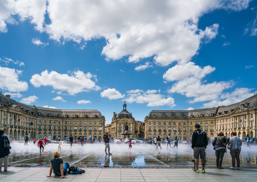 Bordeaux, France, 10 may 2018 : Tourists visiting the Place de la Bourse seen from the boulevard with in front the mirror fountain: 'Mirroir d'eau'
