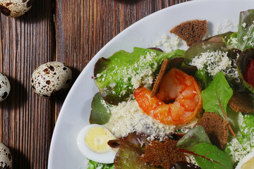 Caesar salad with shrimps and quail eggs top view