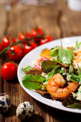 asty fried shrimp in salad on wood background  with cherry tomato
